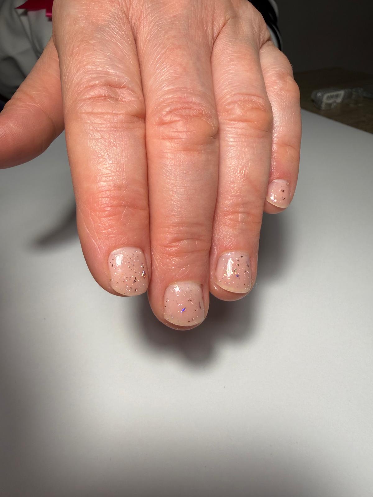 Naturalny manicure z delikatnym brokatem na krótkiej płytce